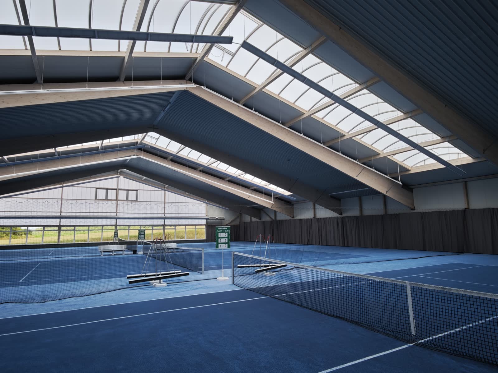 Innenansicht der Tennishalle des TSV Rohr im Juli 2026: beide Teppichplätze, Holzleimbau-Dach mit Lichtbändern